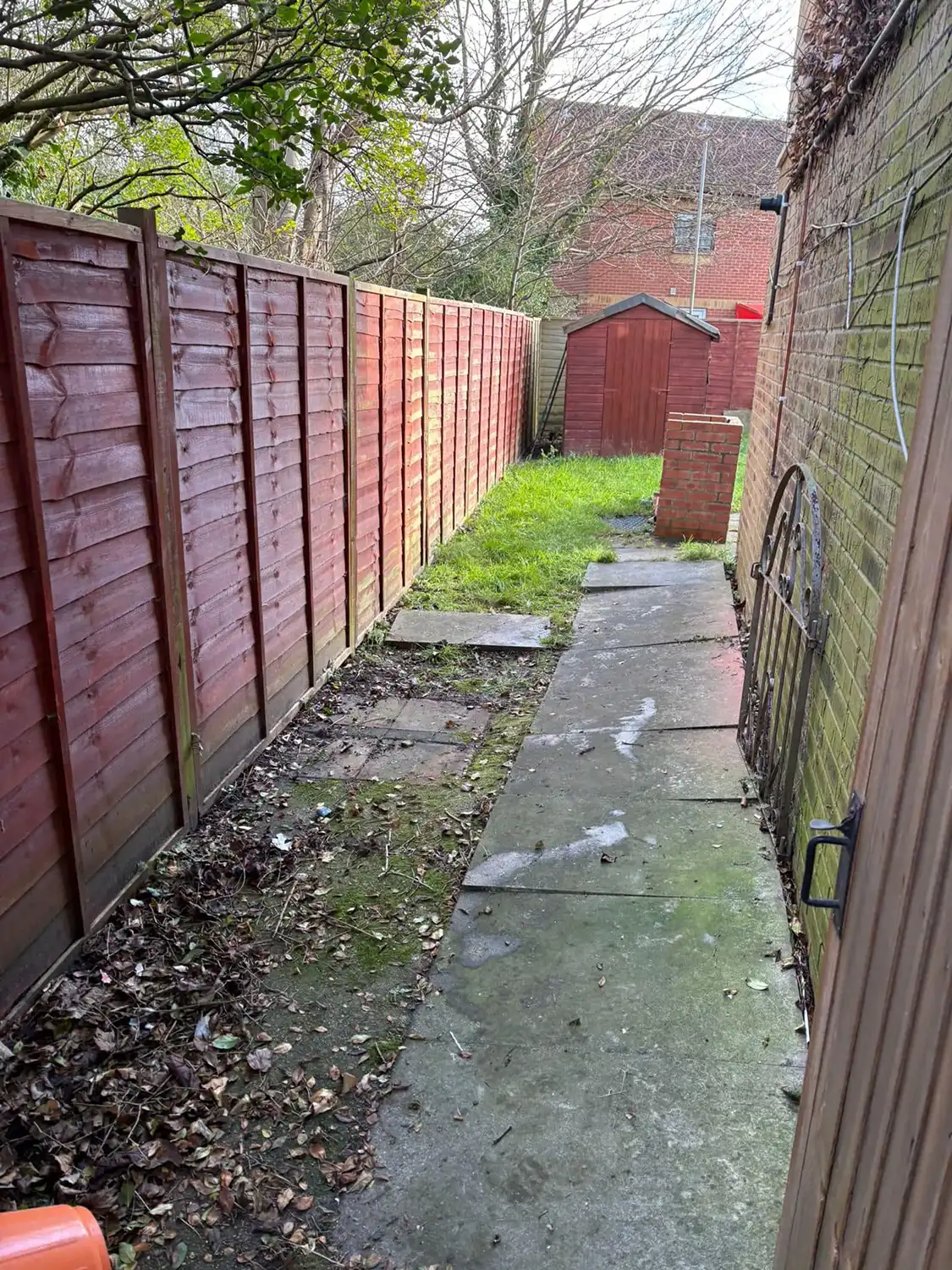 An alley way with a fence and a red shed